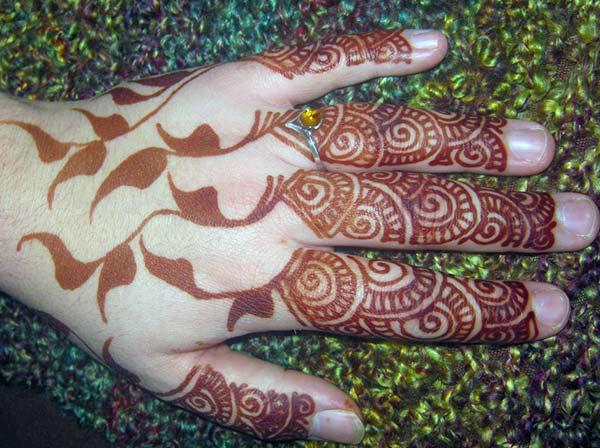 finger mehendi design of swirls and darkened leaves