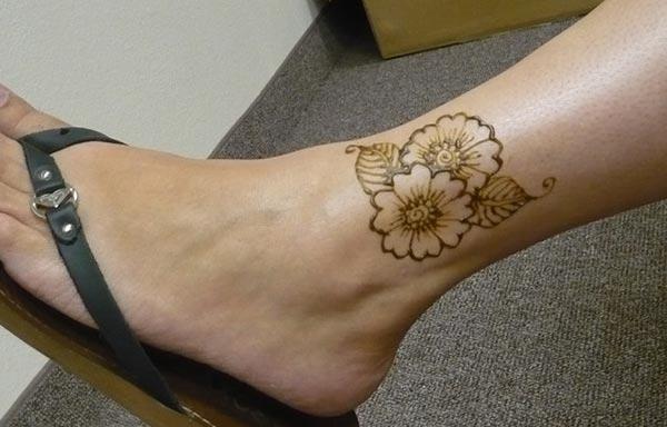 A floral love mehendi design on ankle for Women